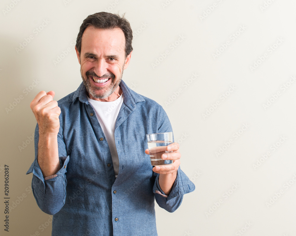 Senior man drinking water in a glass screaming proud and celebrating victory and success very excited, cheering emotion