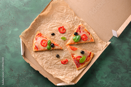 Carton box with slices of delicious pizza on table