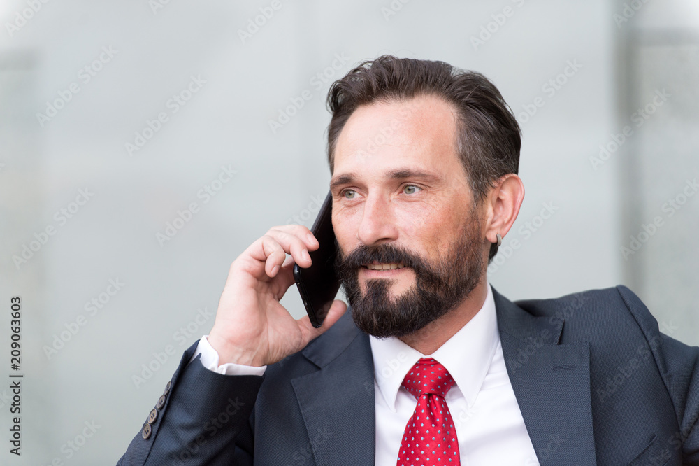 Close up portrait of confident businessman dressed in suit and eyeglasses talking on mobile phone isolated over gray background. business and technology concept - serious businessman with smartphone Close up portrait of confident businessman dressed in suit and eyeglasses talking on mobile phone isolated over gray background. business and technology concept - serious businessman with smartphone