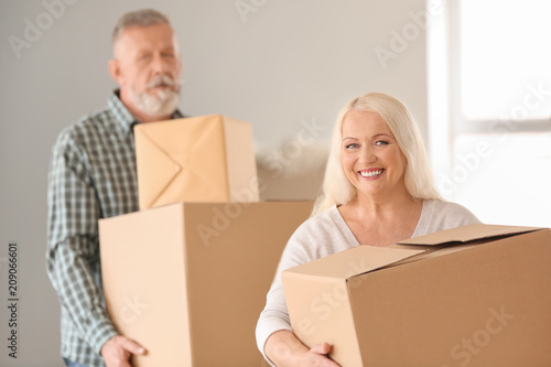 Mature couple with moving boxes at new home © Pixel-Shot