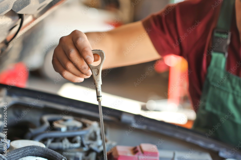 Male mechanic checking level of oil in car engine Male mechanic checking level of oil in car engine
