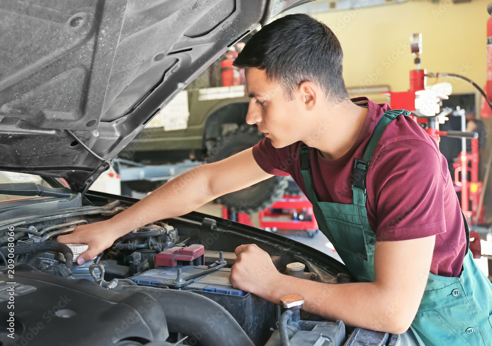 Young auto mechanic repairing car in service center Young auto mechanic repairing car in service center