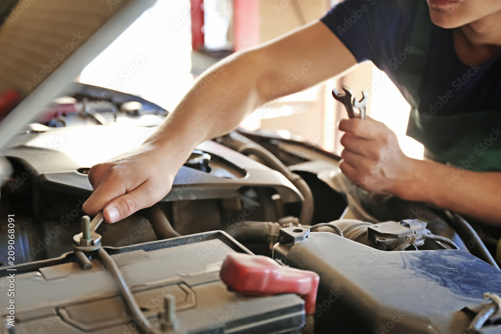 Auto mechanic repairing car in service center, closeup Auto mechanic repairing car in service center, closeup