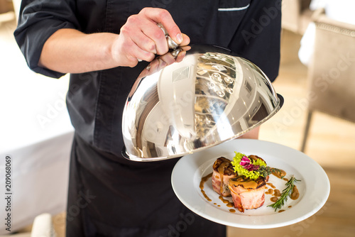 A chef or vaiter holding and shows a dish