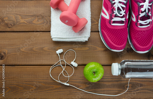  sneakers dumbbells bottle of water and apple