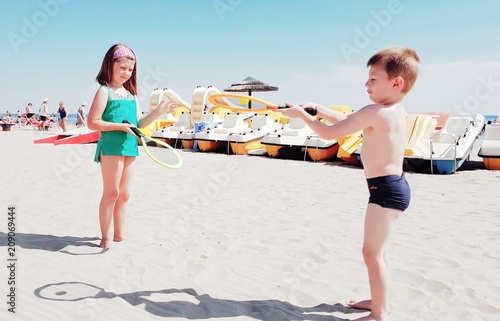 Due bambini giocano con le racchette in spiaggia photo