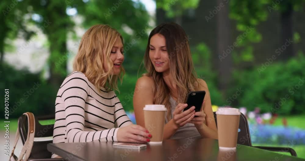 Portrait of couple of happy girlfriends sitting at table taking selfie in European park, Cute white girls seated taking selfie with smart phone in Bruges, Belgium, 4k Portrait of couple of happy girlfriends sitting at table taking selfie in European park, Cute white girls seated taking selfie with smart phone in Bruges, Belgium, 4k