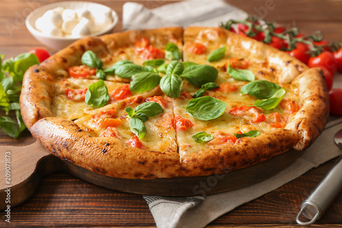 Board with delicious pizza Margherita on wooden table