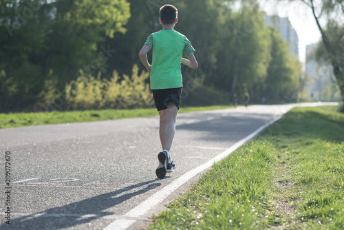 teenager boy in sportswear run on the asphalt road
