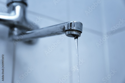 Water pouring from tap, closeup. Water saving concept