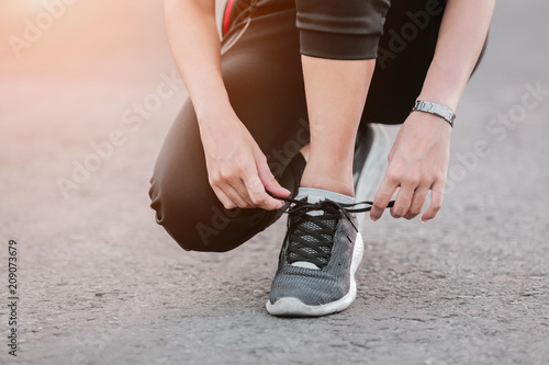 Young woman runner tying shoelaces with copy space  healthy lifestyle and sport concepts.