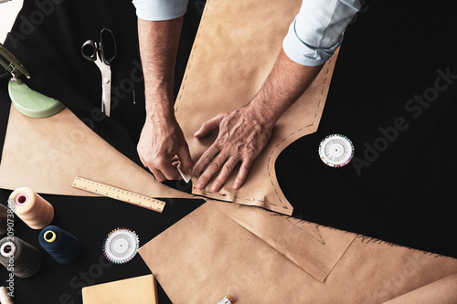 Φωτογραφία Mature tailor working with sewing pattern in atelier