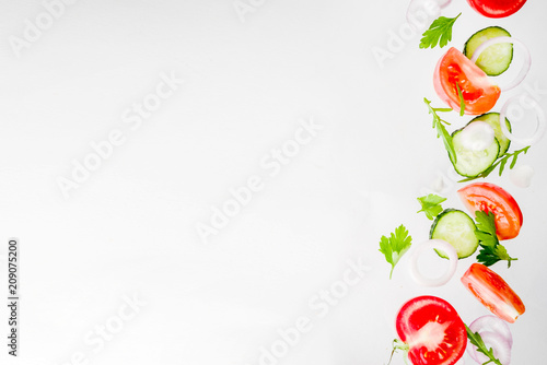 Creative background  layout  concept of fresh healthy diet of salad  fresh raw  vegetables tomatoes parsley onions cucumbers greens  simple pattern on white background