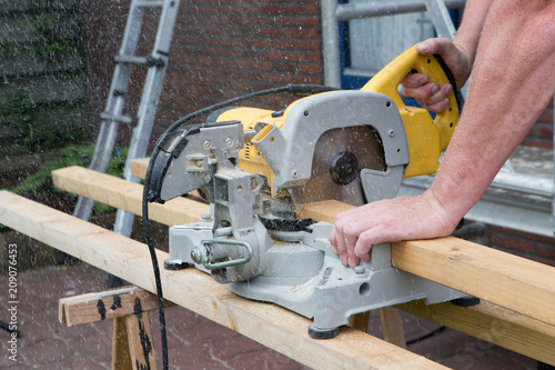 Carpenter. Sawingmachine. Sawingblade. Construction site photo