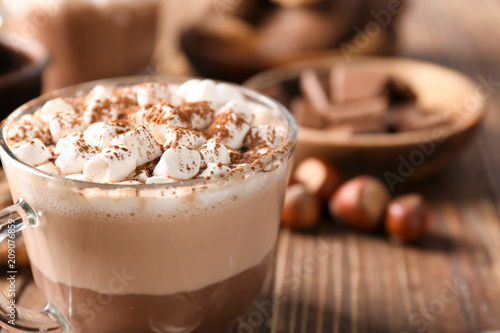 Cup with hot cocoa drink and marshmallows on wooden table, closeup