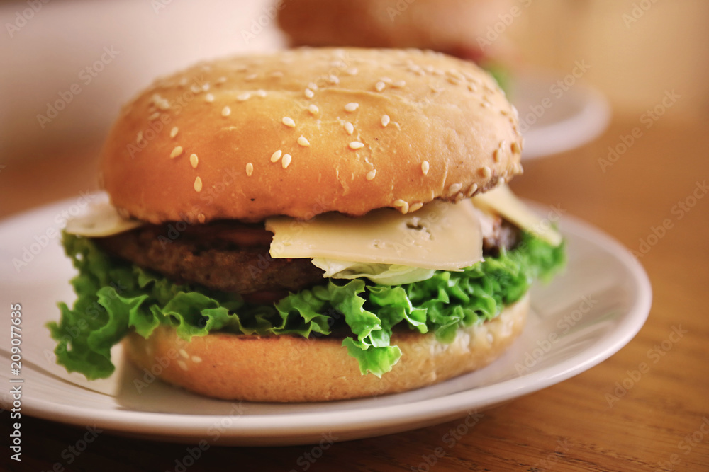 Plate with tasty cheeseburger on table Plate with tasty cheeseburger on table