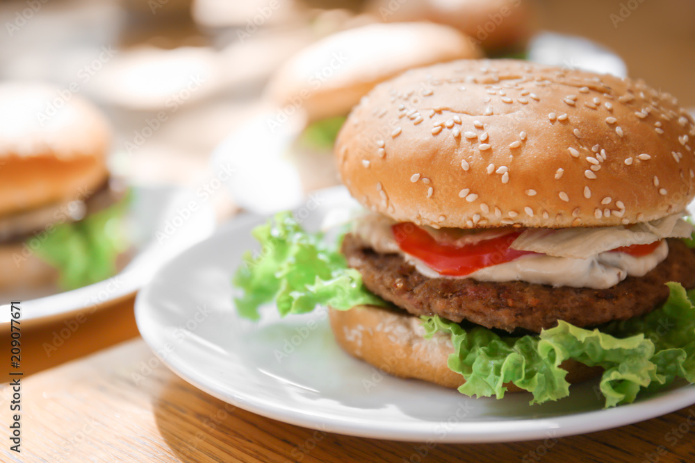 Plate with tasty cheeseburger on table Plate with tasty cheeseburger on table