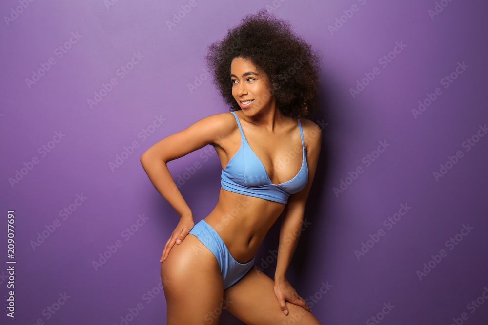 Fototapeta premium Beautiful African-American woman in bikini on color background