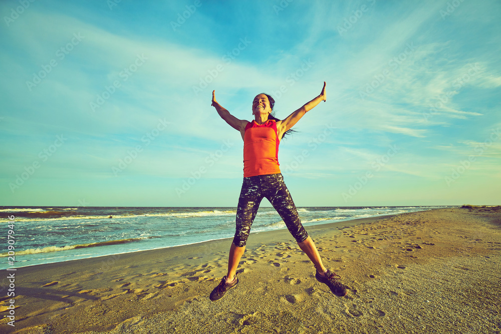 Happy smiling woman jumping on the beach. Happy smiling woman jumping on the beach.