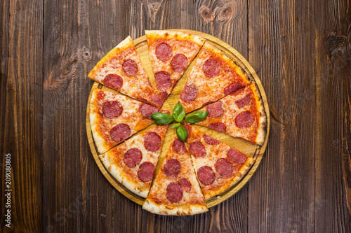 Pizza pepperoni with mozzarella cheese, salami and arugula on wooden background