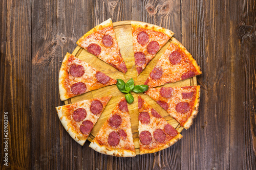 Pizza pepperoni with mozzarella cheese, salami and arugula on wooden background