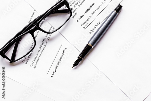 Signing the contract with pen and glasses in business work top v