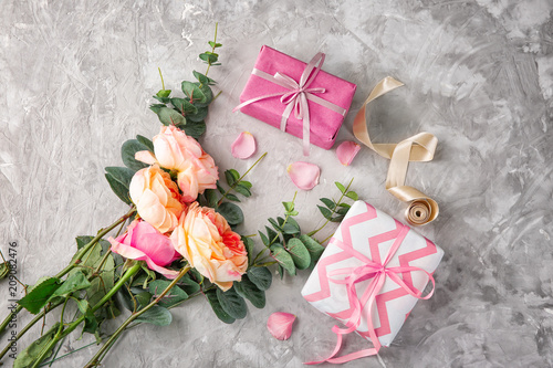 Composition with beautiful flowers and gift boxes on grey background