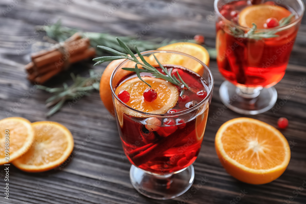 Beverage with cinnamon, orange and cranberry in glass on wooden table Beverage with cinnamon, orange and cranberry in glass on wooden table