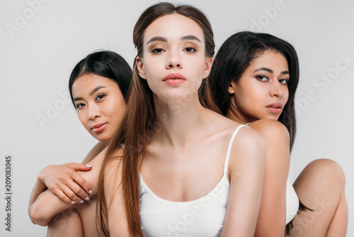 charming multicultural girls posing together, isolated on grey