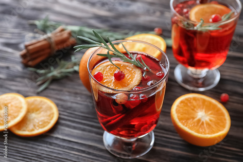 Beverage with cinnamon, orange and cranberry in glass on wooden table