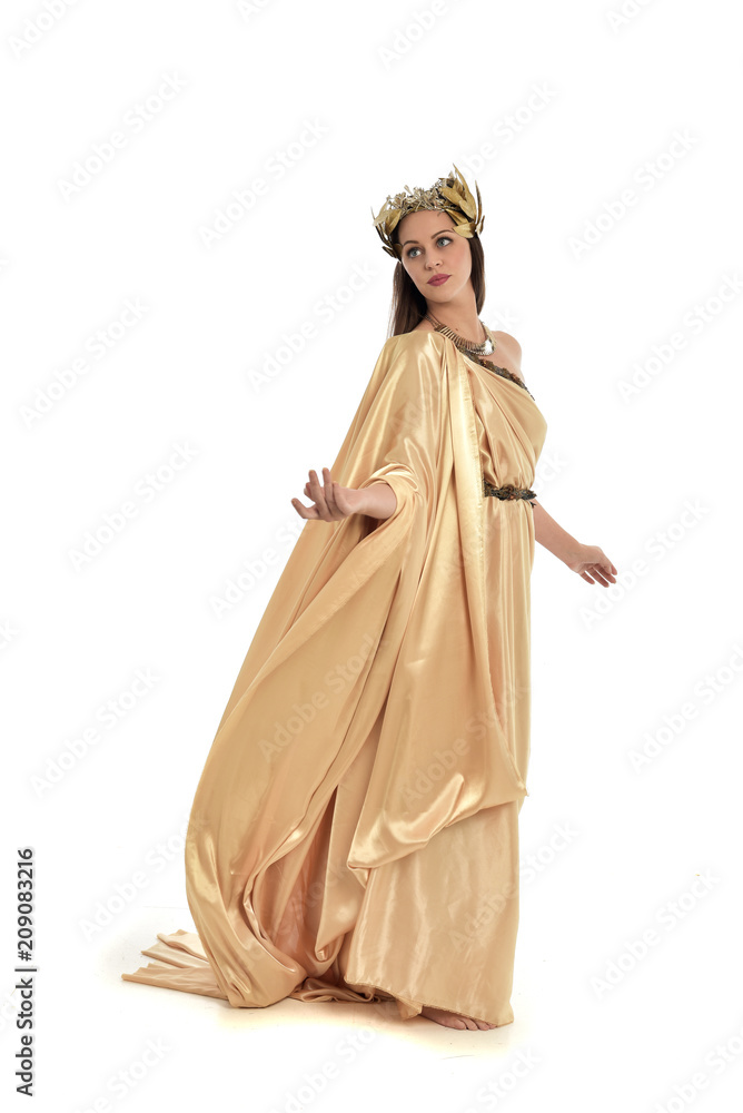 full length portrait of brunette woman wearing long golden grecian gown, standing pose. isolated on white studio background.