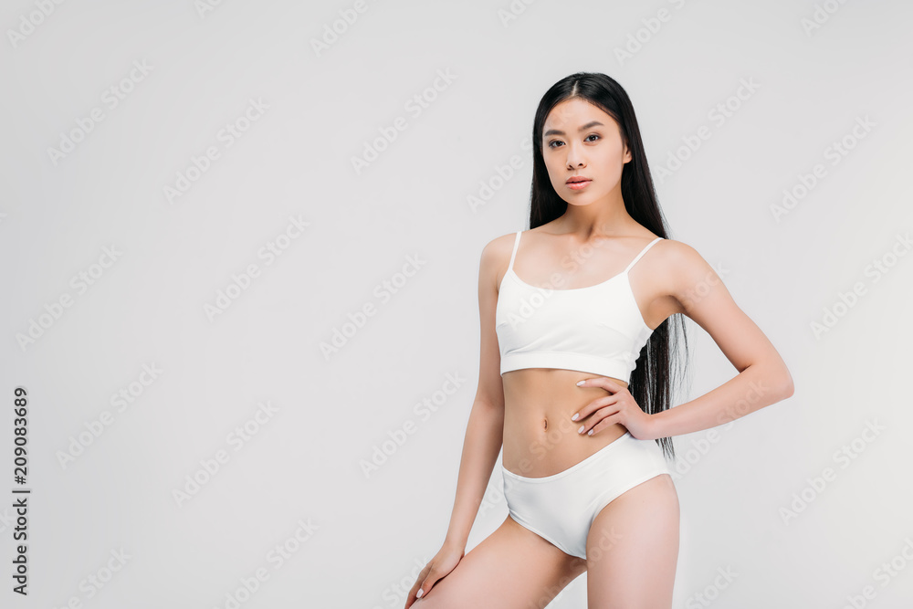 beautiful asian girl posing in white panties and bra, isolated on grey  Photos | Adobe Stock