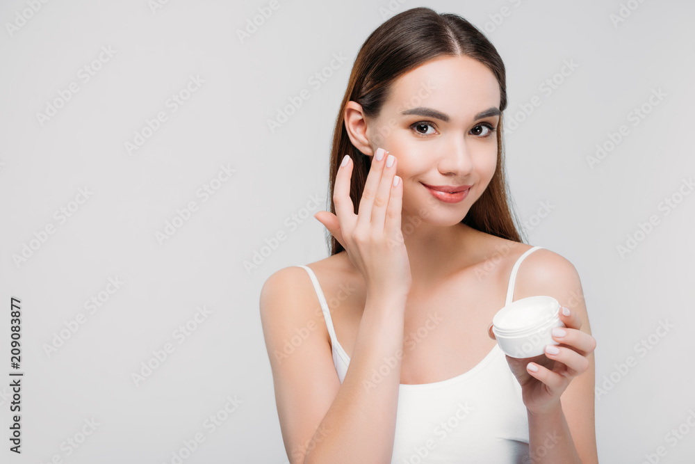 beautiful girl applying cosmetic cream on face, isolated on grey beautiful girl applying cosmetic cream on face, isolated on grey