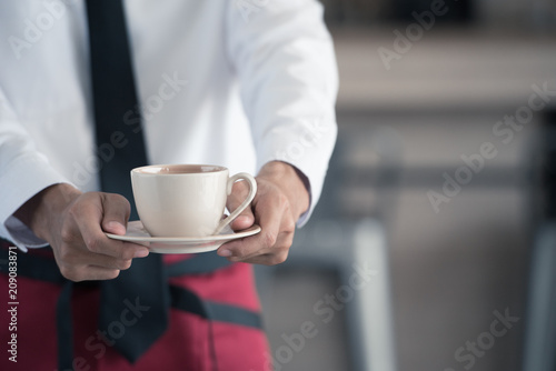 Close up of waiter serving coffee in cafe.