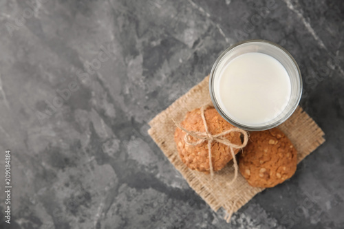 Delicious oatmeal cookies and glass of milk on grey background