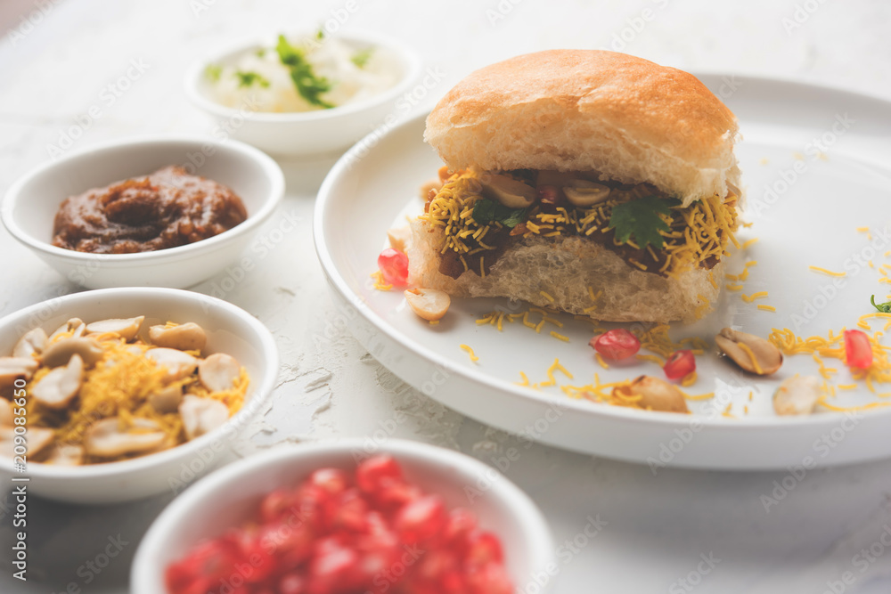 Dabeli is an Indian snack item served with Pomegranate Seeds and Cilantro in white ceramic plate. It's a popular Navratri Festival food Dabeli is an Indian snack item served with Pomegranate Seeds and Cilantro in white ceramic plate. It's a popular Navratri Festival food
