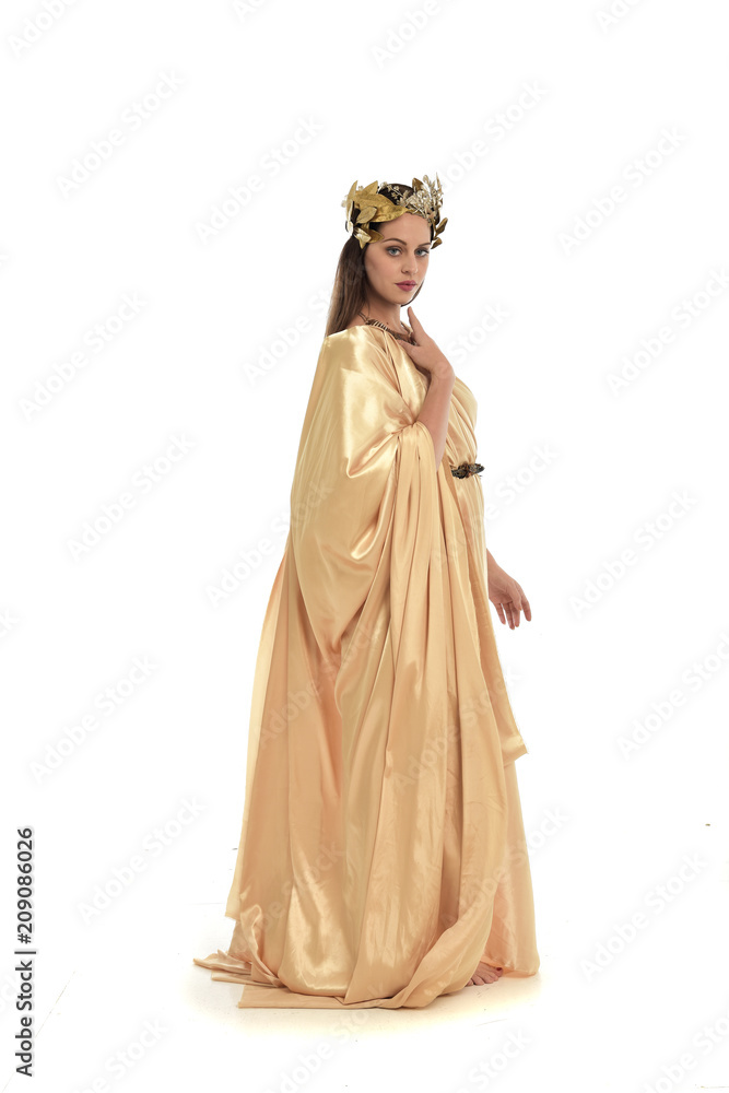 full length portrait of brunette woman wearing long golden grecian gown, standing pose. isolated on white studio background.
