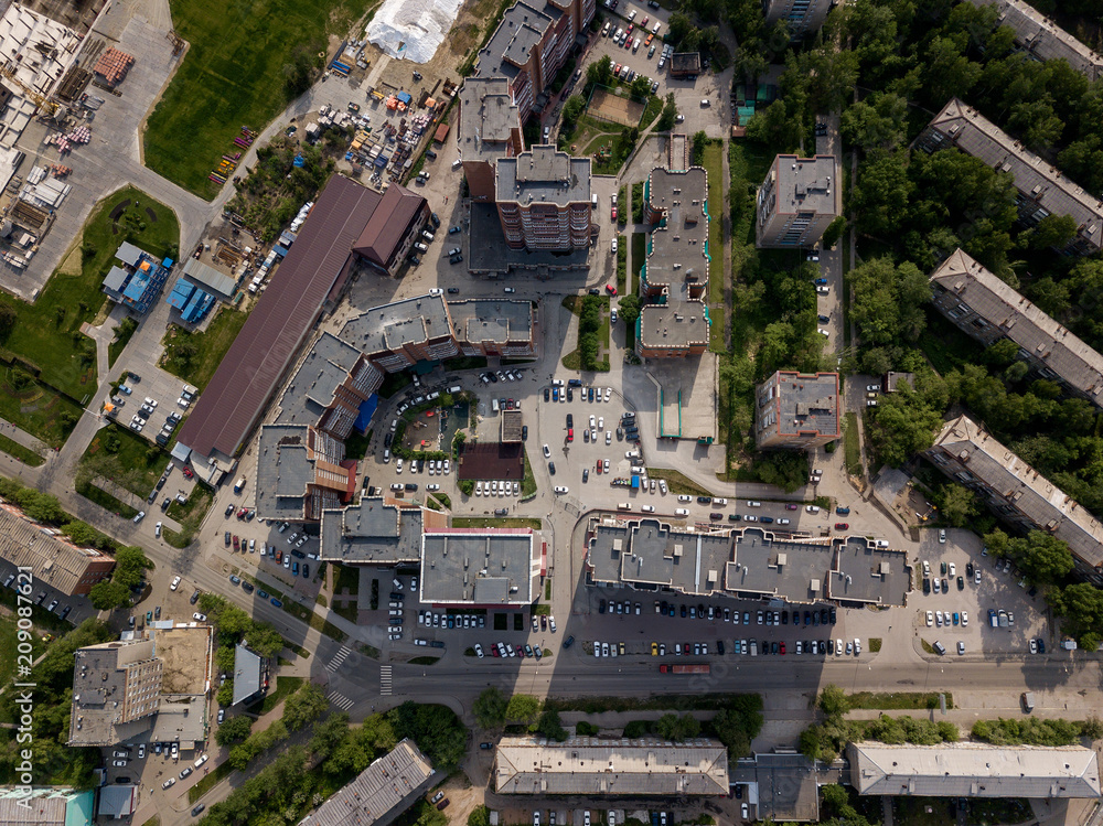 Aerial view of old and new russian buildings in green area in the city with a lot of cars. Russian streets, Novosibirsk. Dachnaya Street with parking