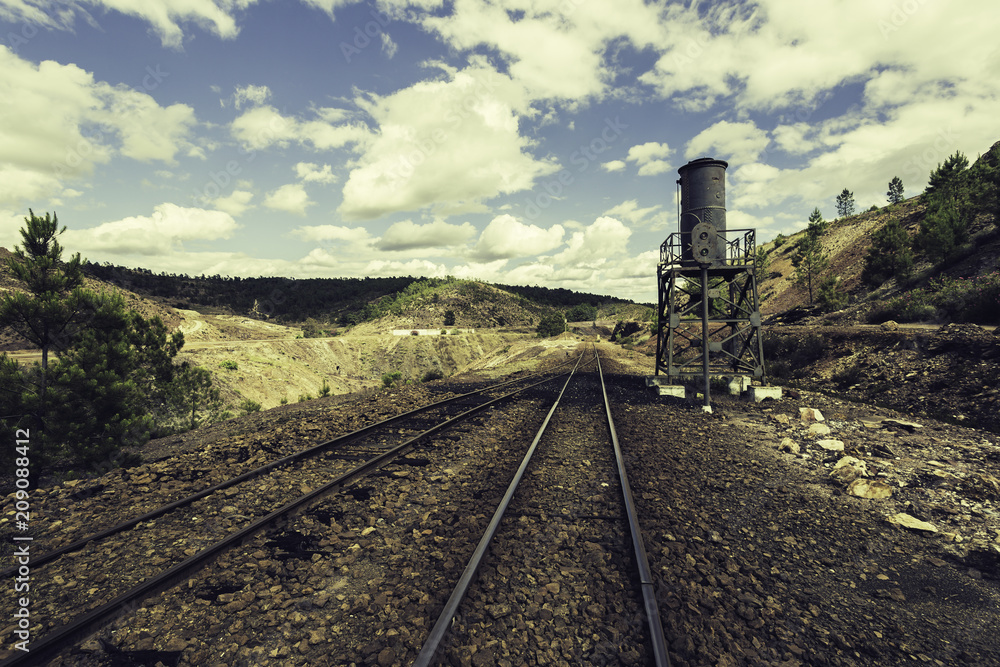 Old railway road in mining landscape, with traffic light and water tank on the side