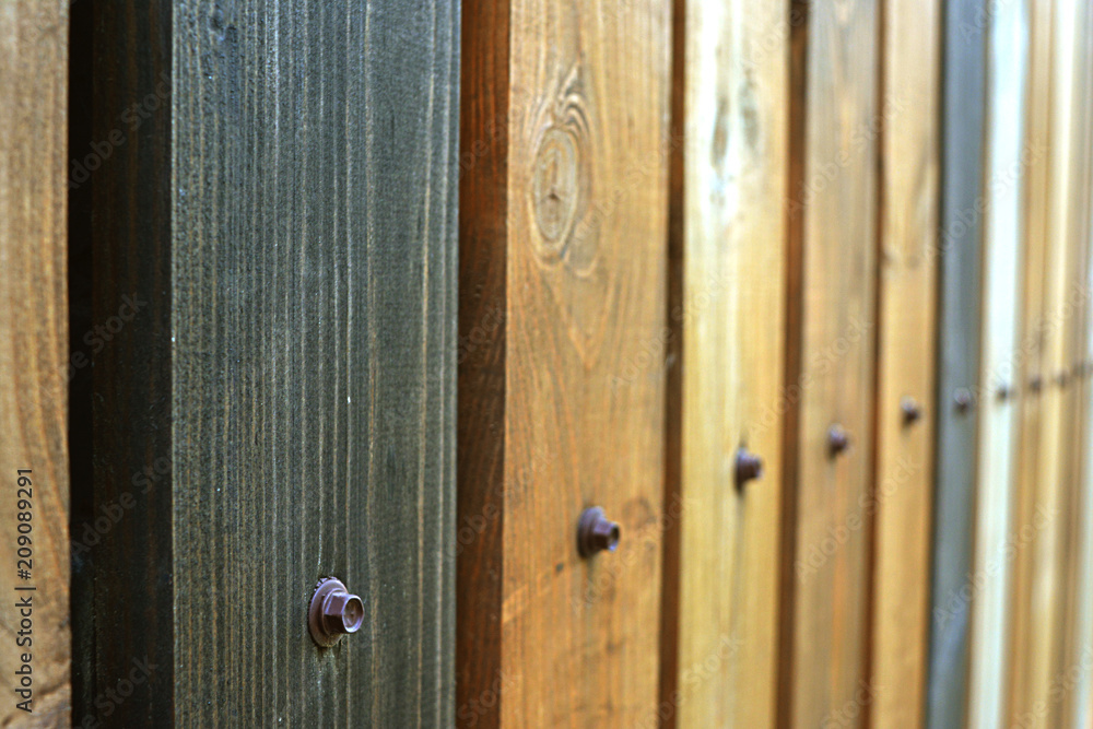 Obraz premium Fence as a background of multicolored wooden boards, with nails vertical texture in perspective.