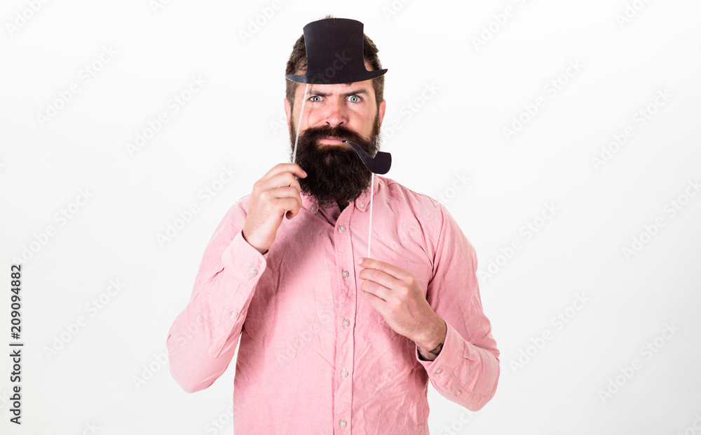 Guy smokes tobacco pipe. Hipster with beard and mustache on serious face posing with photo booth props. Aristocracy concept. Man holding paper party props tobacco pipe and top hat, white background Guy smokes tobacco pipe. Hipster with beard and mustache on serious face posing with photo booth props. Aristocracy concept. Man holding paper party props tobacco pipe and top hat, white background