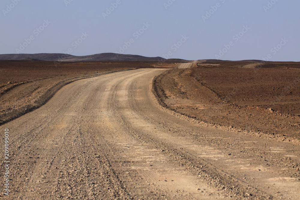szeroka szutrowa droga przez piaszczyste pustkowie