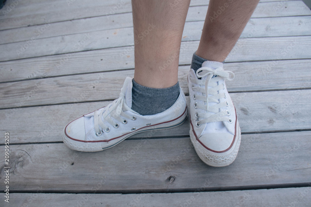Feet in a pair of canvas shoes on wood floor, Canvas shoes walking on wooden Feet in a pair of canvas shoes on wood floor, Canvas shoes walking on wooden