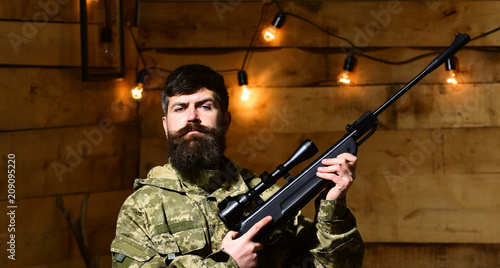 Photography Man with beard wears camouflage clothing in wooden interior background