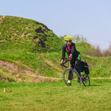 Sporty woman cyclist riding bike on green grass