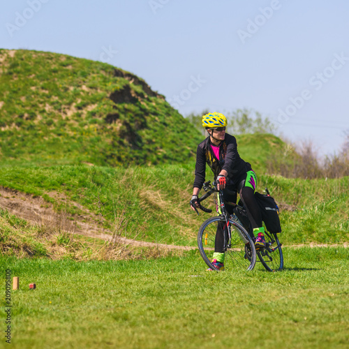 Sporty woman cyclist riding bike on green grass