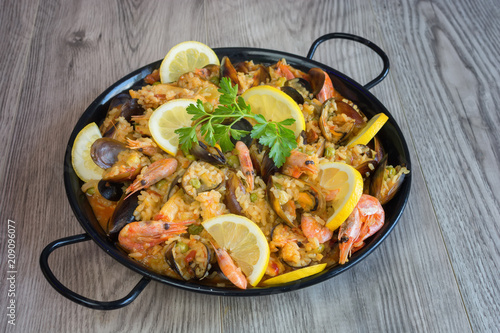 Traditional spanish seafood paella in pan rice, peas, shrimps, mussels, squid on light grey concrete background