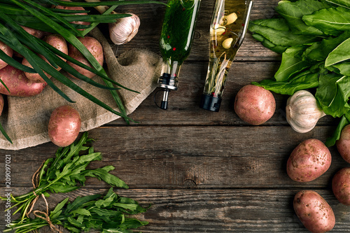 Fresh potatoes, oil, garlic and spicy herbs on a kitchen wooden background. photo