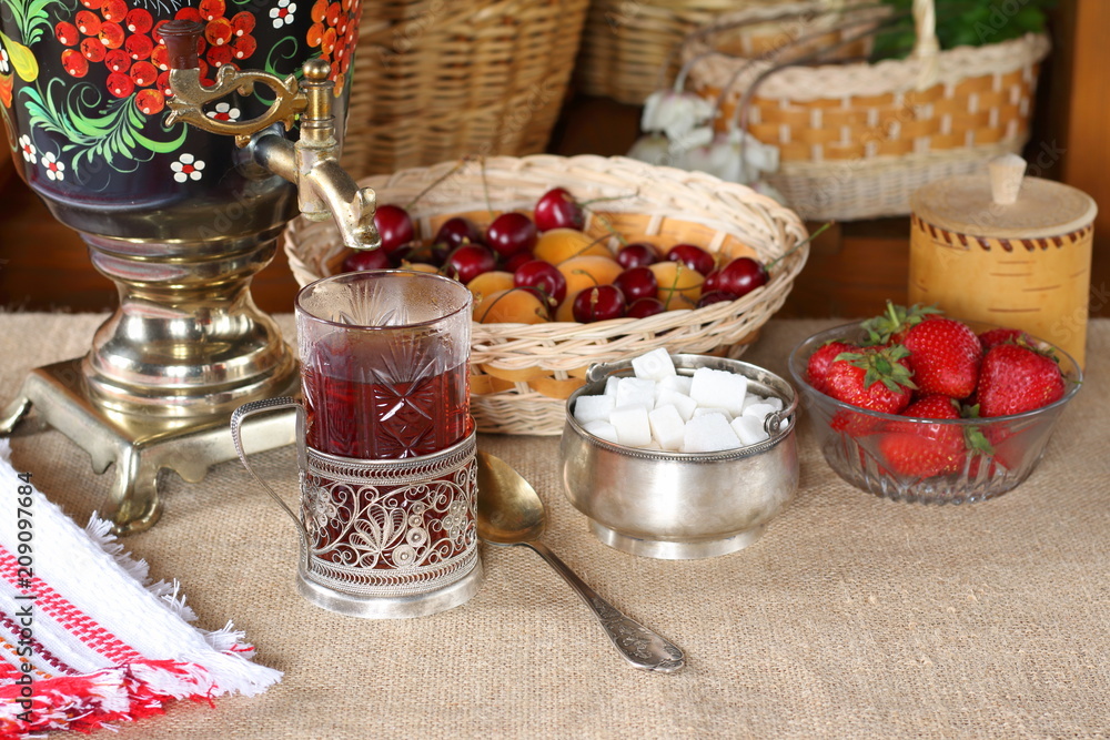 A glass of black tea, samovar and summer berries and fruits.