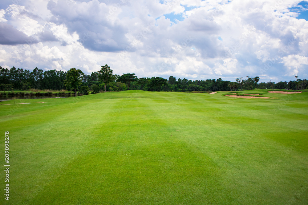 Green golf course fairway with sands and water hazard in cloudy day Green golf course fairway with sands and water hazard in cloudy day